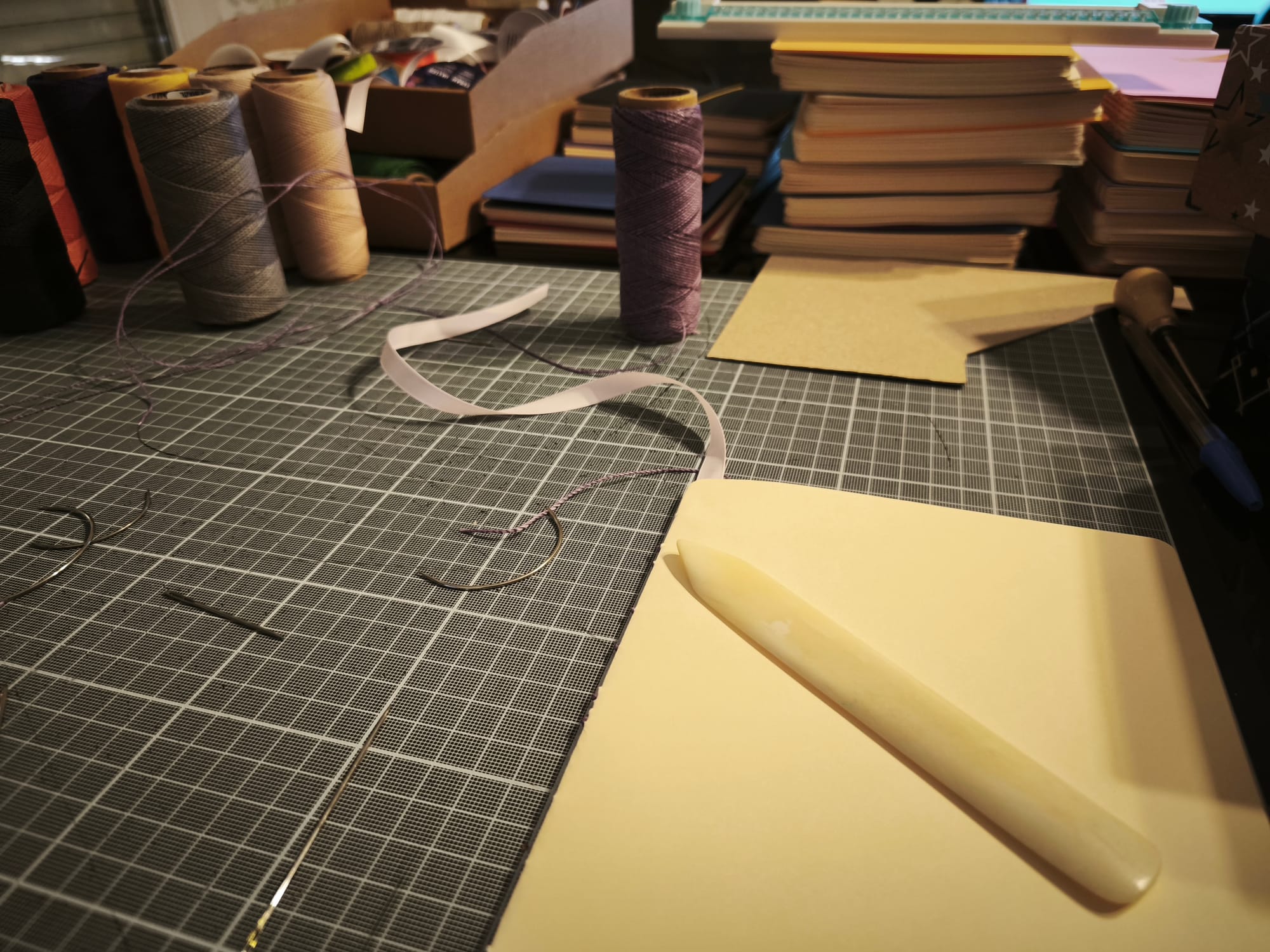 Des outils de reliure et des carnets en cours posés sur une table